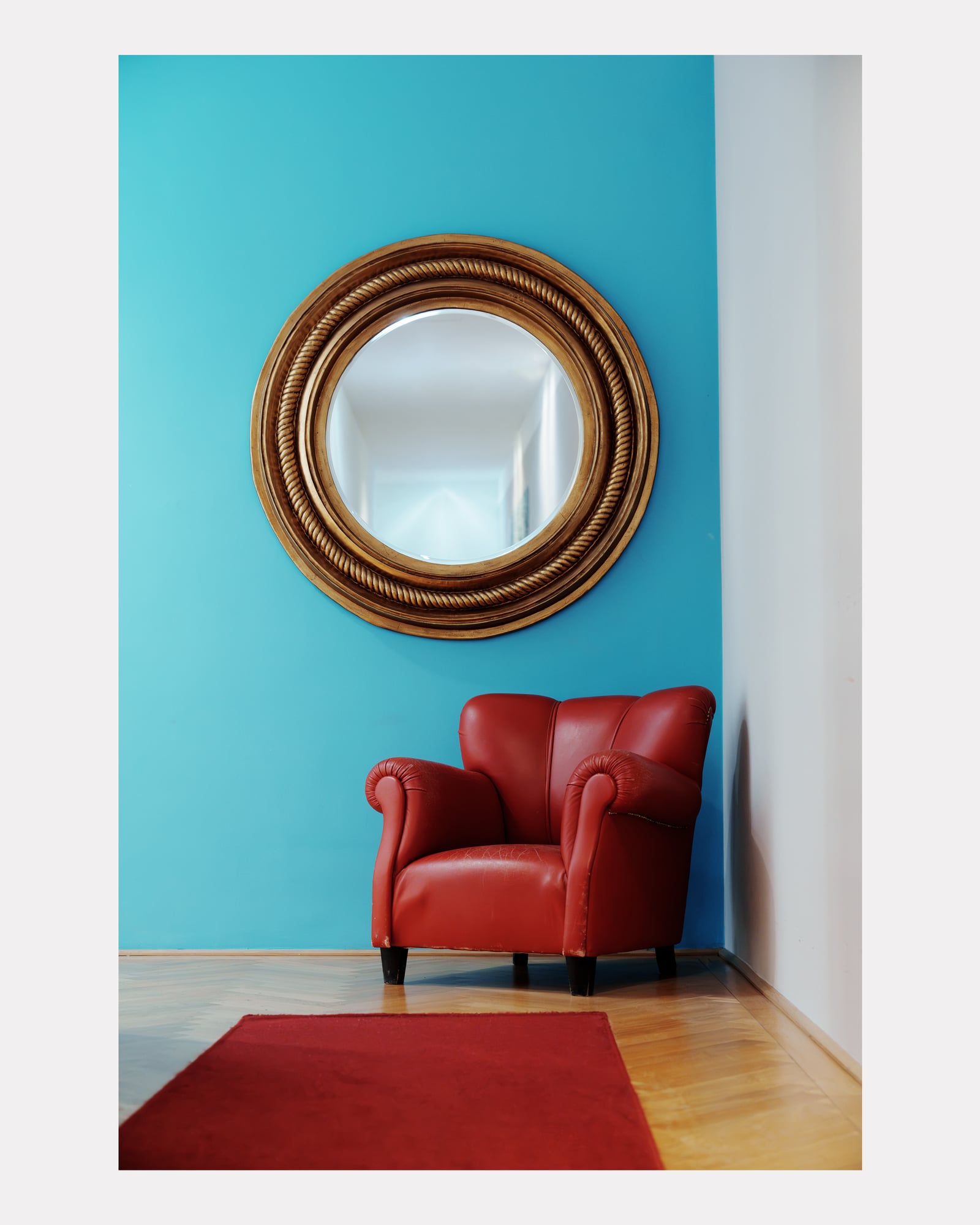 Fauteuil club rouge et miroir doré sur mur bleu turquoise, hôtel Altstadt Vienna