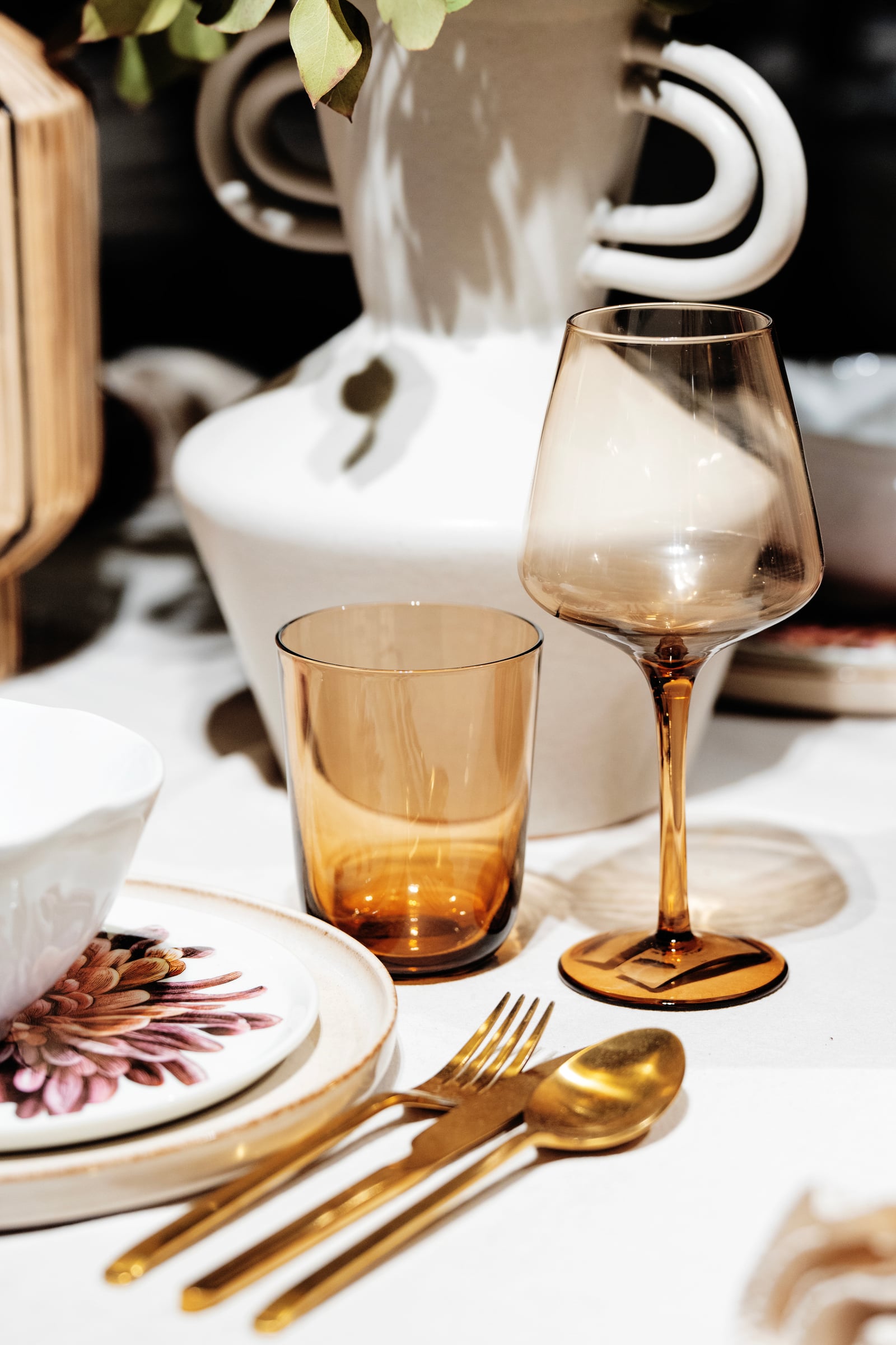 Verres ambrés, couverts dorés et vase sculptural sur une table dressée, H&M Home