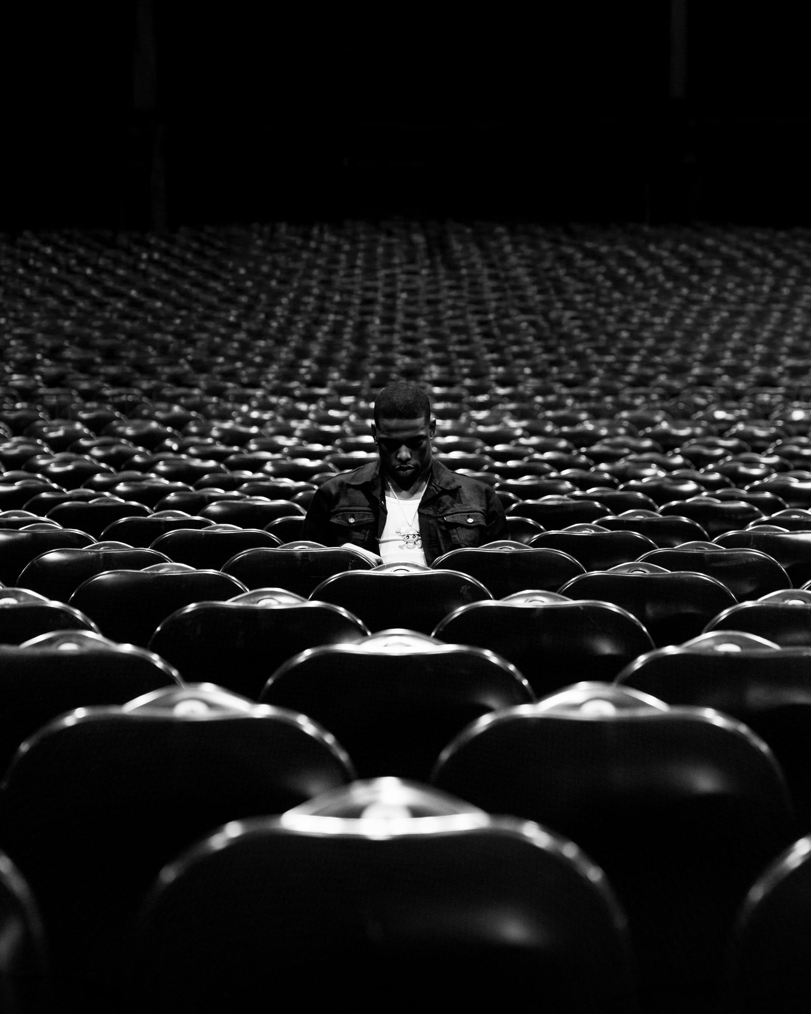 Patrick Habirora assis seul au milieu d'une salle de spectacle vide, en noir et blanc